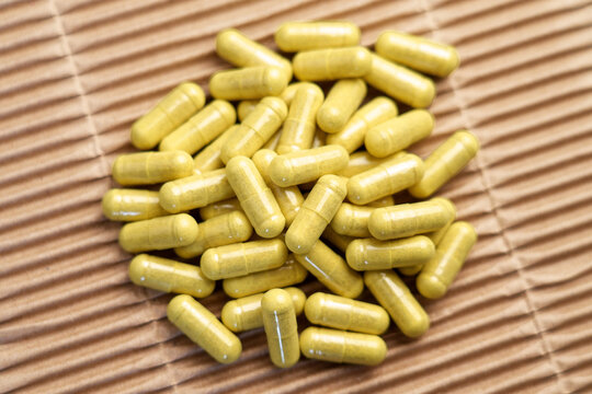 Green quercetin capsules on paper background. Dietary supplements with bromelain extract for immune support. Top view. 