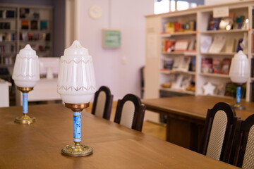 Vintage lamps on a table in a traditional public library with bookshelfs