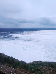 Dramatic ocean view with powerful waves crashing against the shore under a moody sky. Evokes feelings of strength, resilience,  natural beauty. Perfect for travel, weather,  emotional concepts.