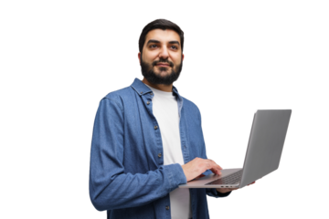 Young Man Engaging With a Laptop While Standing Against a Plain White Backdrop During a Creative Session