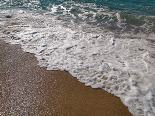 A serene beach at midday with gentle waves lapping the shore and clear blue skies inviting relaxation