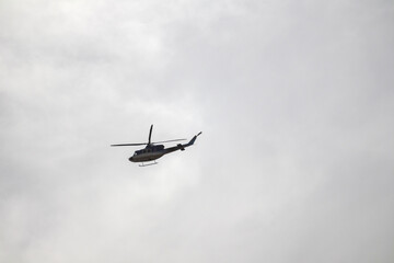 
a helicopter flying high in a cloudy sky.