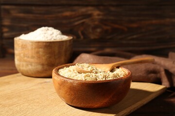 Brown rice and flour on wooden table, closeup. Space for text