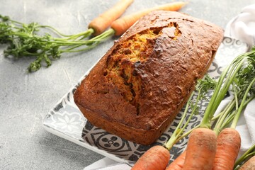 Tasty carrot cake and vegetables on grey textured table, closeup