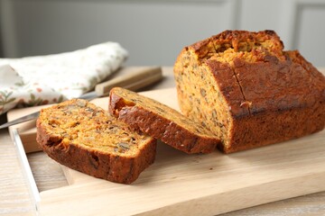 Cut homemade carrot cake with nuts and knife on wooden table, closeup
