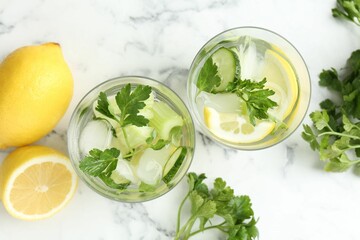 Healthy drink with parsley, cucumbers, lemons and celery on white marble table, flat lay