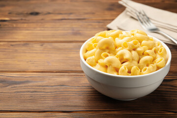 Delicious macaroni and cheese served on wooden table, closeup. Space for text
