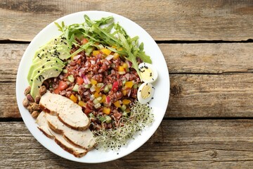 Tasty salad with brown rice on wooden table, top view. Space for text