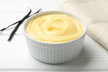 Tasty vanilla pudding and pods on white wooden table, closeup