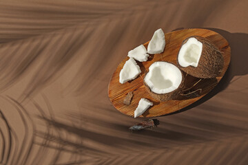 Fresh coconut and shadow cast by tropical palm on beige background, top view. Space for text