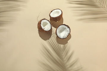 Fresh coconuts and shadow cast by tropical palm on beige background, flat lay. Space for text