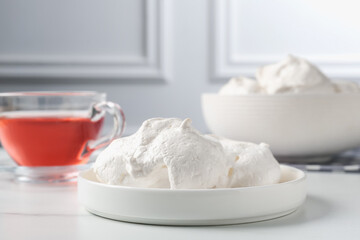 Delicious homemade meringue cookies and tea on light table, closeup
