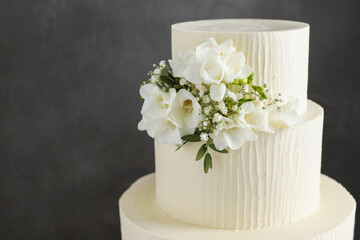 Delicious wedding cake with floral decor on grey background, closeup. Space for text