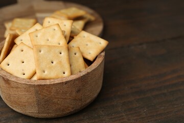 Tasty salty crackers on wooden table, closeup. Space for text