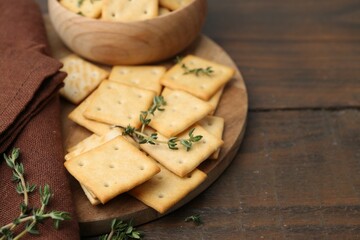 Tasty salty crackers with thyme on wooden table, closeup