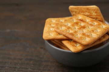 Tasty salty crackers on wooden table, closeup. Space for text