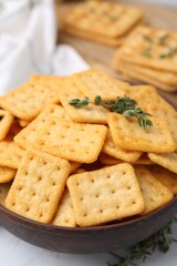 Tasty salty crackers and thyme on white table, closeup