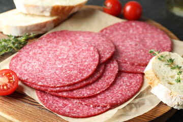 Slices of tasty smoked sausage, tomatoes, thyme and bread on table, closeup