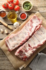 Raw pork ribs, spices and tomatoes on wooden table, flat lay