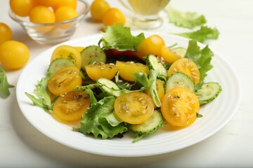 Fresh salad with yellow tomatoes on white table, closeup