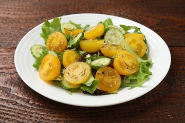 Fresh salad with yellow tomatoes on wooden table, closeup