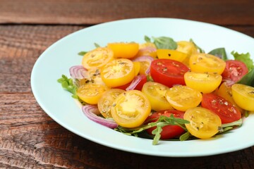 Fresh salad with yellow tomatoes on wooden table, closeup
