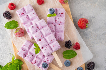 Homemade berry ice cream or popsicles with mint leaves on a gray concrete background. Delicious...