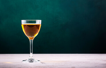 French calvados brandy in glass on dark green background