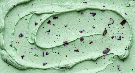 Close-up shot of swirled mint chocolate chip ice cream, showing texture and dark chocolate.