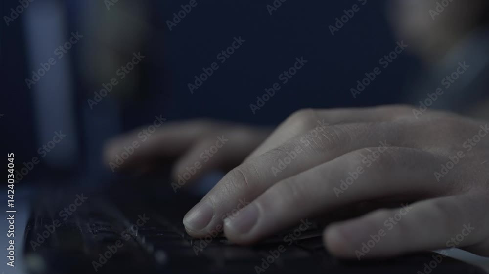 Aufkleber typing on computer keyboard at night with dim lighting and focused atmosphere