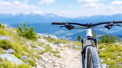 A mountain bike handlebar and front wheel on a scenic trail overlooking distant mountains.
