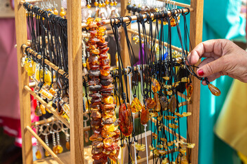 Amber beads in a street shop. The hand in the frame selects amber beads. Souvenir the Baltic Sea