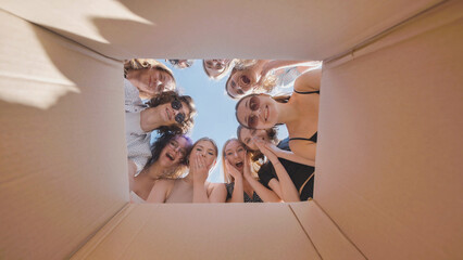 High school students eagerly looking inside a big cardboard box, uncovering a summer break surprise