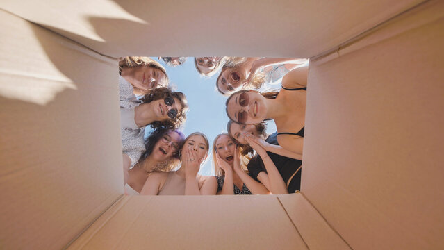 High school students eagerly looking inside a big cardboard box, uncovering a summer break surprise