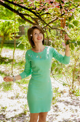 Girl walking in the park in green dress on spring garden.