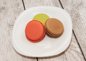 Color macarons lie on a plate. Delicious cookies on a plate on a light background