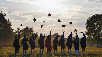 Graduates joyfully tossing caps in the air at sunset, marking the end of their academic journey and...