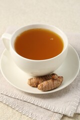 Aromatic turmeric tea and rhizomes on white textured table, closeup