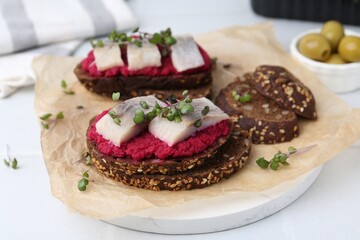 Tasty sandwiches with herring and horseradish sauce on white table, closeup