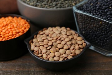 Different types of lentils on wooden table, closeup