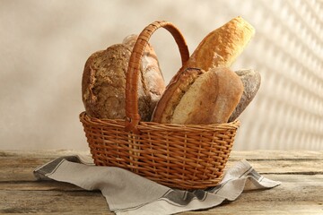 Different loaves of fresh bread in basket on wooden table, closeup