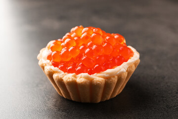 Tasty canape with red caviar on grey table, closeup