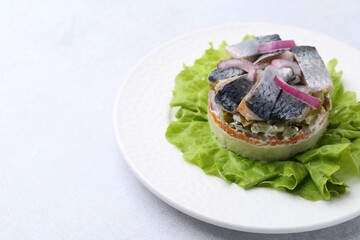 Delicious salad with herring and vegetables on light grey table, closeup. Space for text