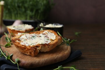 Tasty bread with garlic, herbs and oil on wooden table, closeup. Space for text