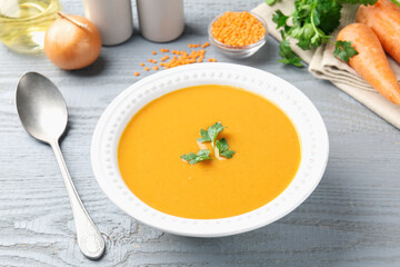 Delicious lentil cream soup served on grey wooden table, closeup
