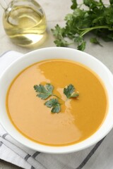 Delicious lentil cream soup with parsley and oil on light grey table, closeup