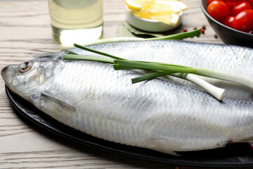 Salted herrings, spices and tomatoes on wooden table, closeup