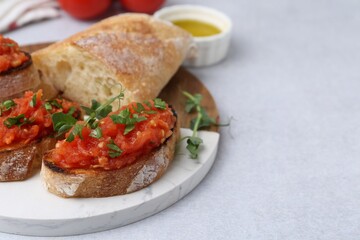 Tasty bread with tomato, parsley and oil on light table, closeup. Space for text