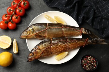Delicious smoked herrings with lemon slices and other products on black table, flat lay © New Africa