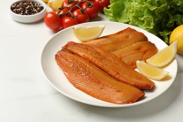 Delicious smoked herring fillets with lemon slices and other products on white table, closeup